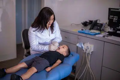Dr. Jessie Trinh-Moore providing pediatric dental care for a patient during his emergency visit to Sycamore Smiles in Fort Worth, TX