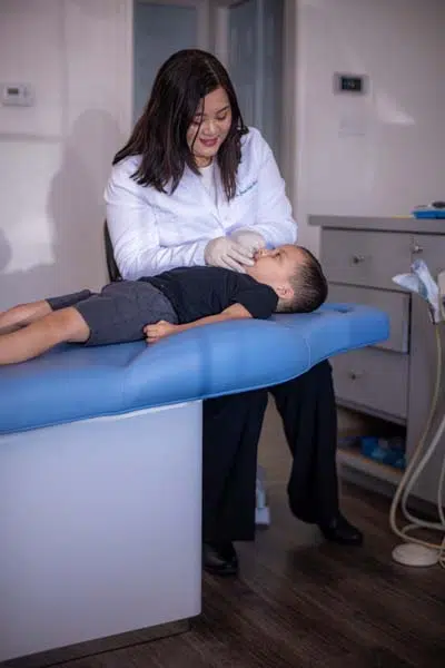 Dr. Jessie Trinh-Moore providing dental care for her pediatric patient at Sycamore Smiles in Fort Worth, TX