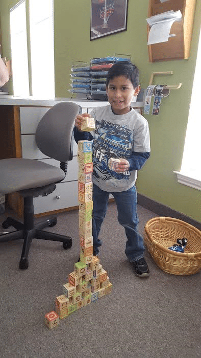 Young boy playing with the toys in the waiting room at Sycamore Smiles which is designed for quality and fun pediatric dentistry.