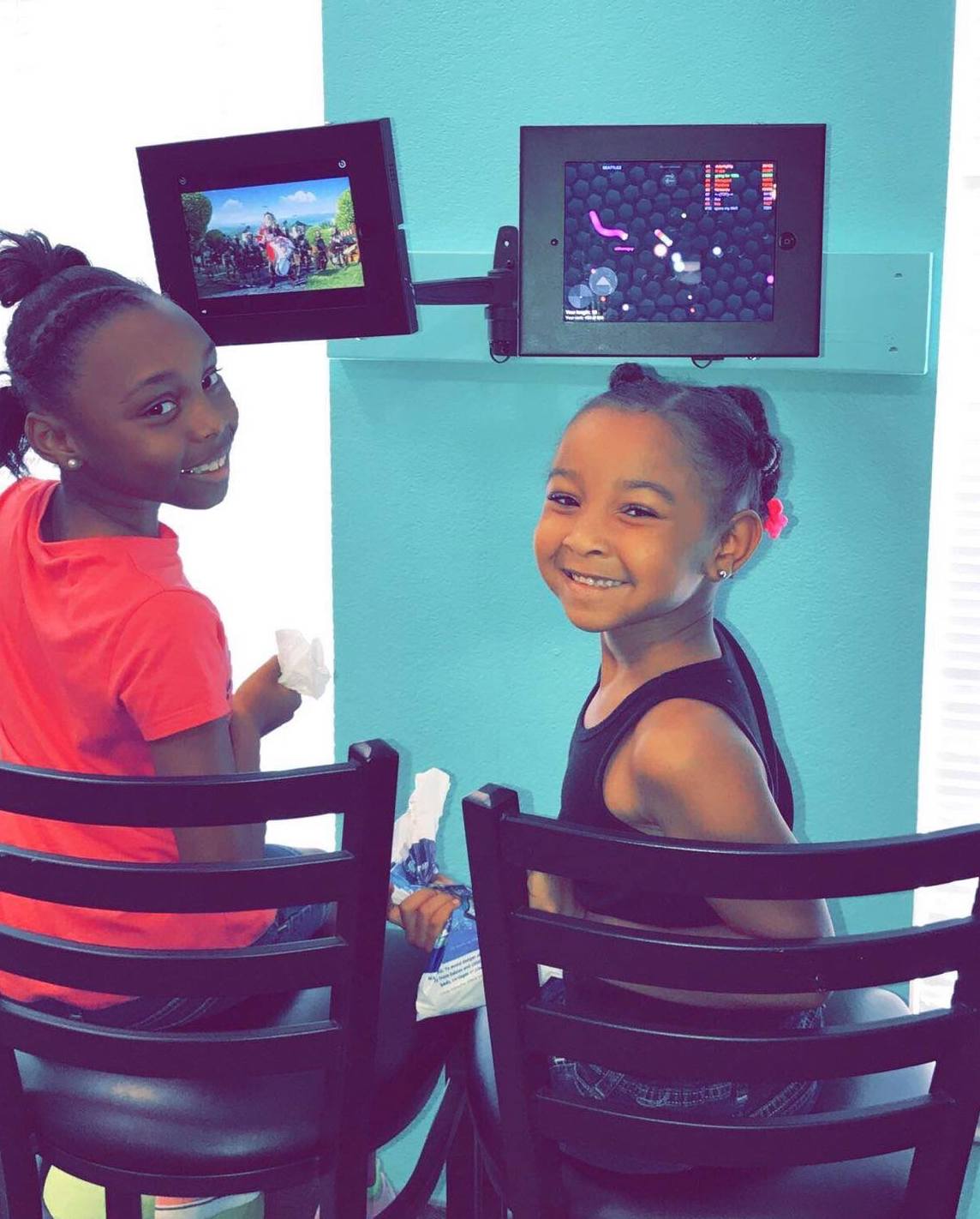 Two young girls watching videos to help them relax before their dental visit that also uses sedation dentistry to help relieve them of any anxiety during treatment. 